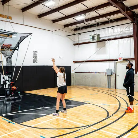 girl and coach practicing with APEX basketball shooting machine by PowerArc Sports