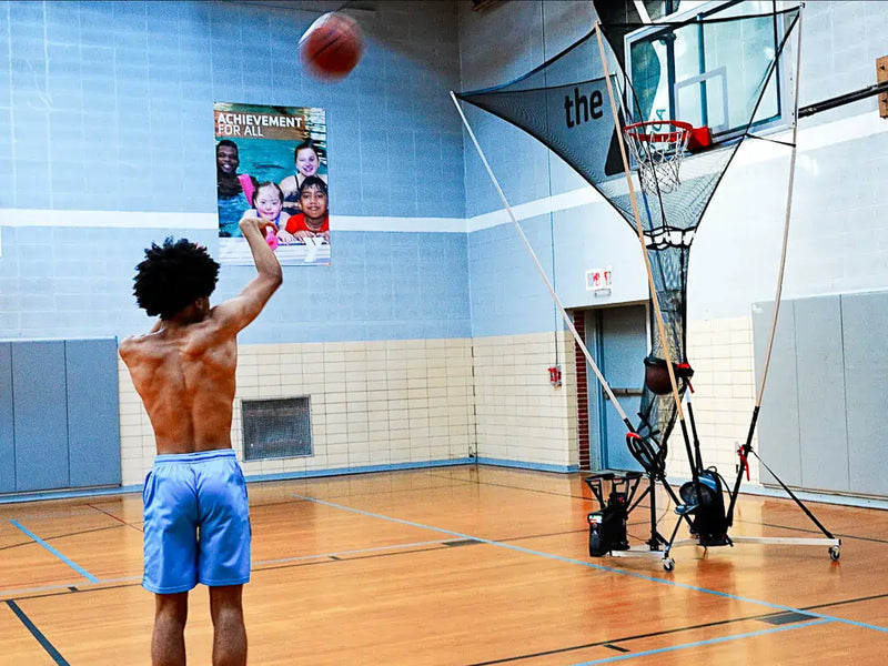 boy practicing with APEX basketball shooting machine at gym