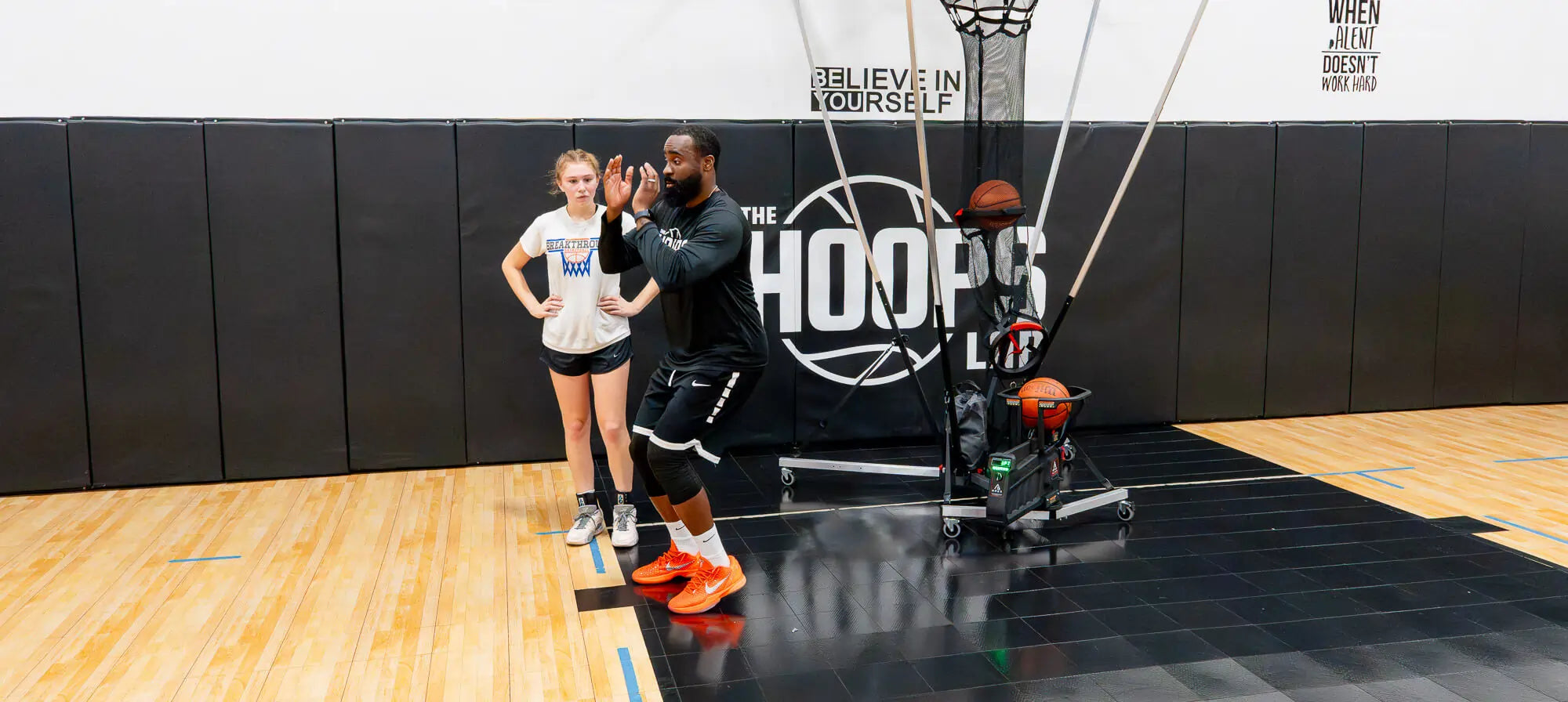 basketball girl player and coach standing next to APEX basketball shooting machine by PowerArc 